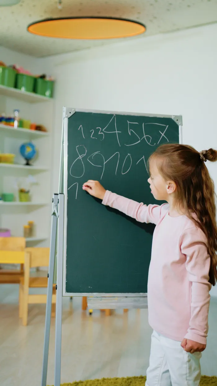 Дитина пише цифри на дошці під час підготовки до школи